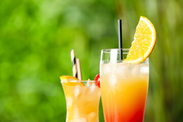 Glasses of tasty Tequila Sunrise cocktail outdoors, closeup