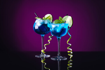 Glasses of Blue Lagoon cocktail on dark color background