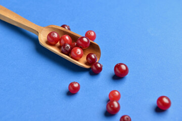 Spoon with tasty fresh cranberries on color background, closeup