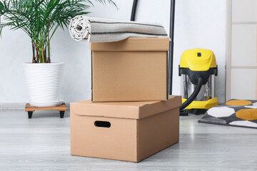 Cardboard boxes with rolled carpet in room