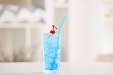 Glass of Blue Lagoon cocktail on table in room