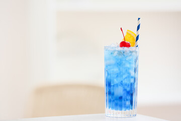Glass of Blue Lagoon cocktail on table in room