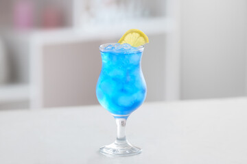 Glass of Blue Lagoon cocktail on table in room