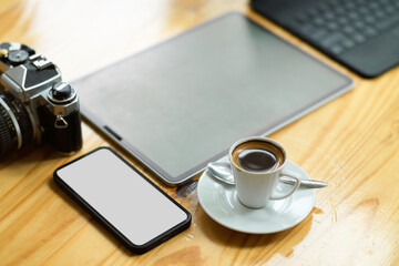 Modern digital tablet, smartphone, vintage camera and coffee cup on wooden table