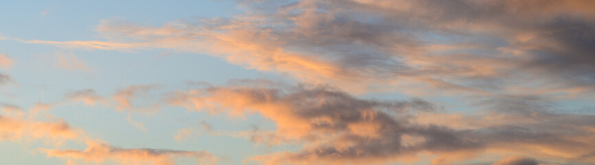 Dramatic sunset with light blue sky and colorful bright clouds, as a nature background
