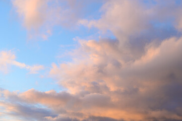 Fluffy ethereal pastel clouds lighted by the fading sun, as a nature background
