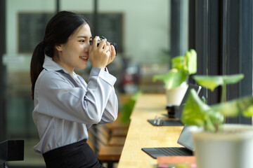 Young businesswoman sits in cafe using retro camera taking outside view