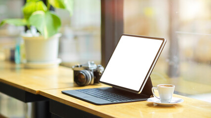 Modern digital tablet computer white screen mockup with keyboard stand on wooden table