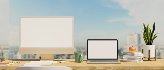 Working space with computer and laptop blank screen mockup over city sky view in background.