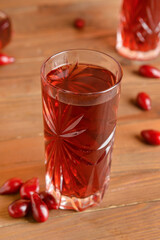Glass of healthy dogwood berry drink on wooden background
