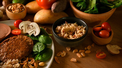 Vegan meat with brown rice, nuts and vegetables on a wooden table.