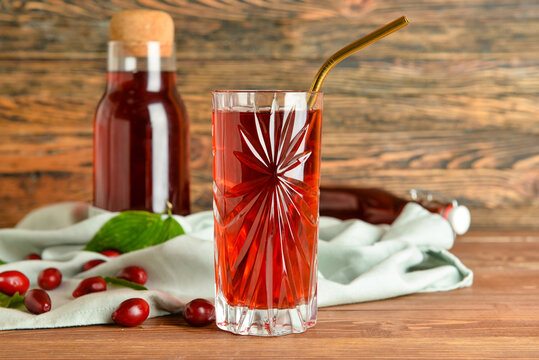Glass of healthy dogwood berry drink on wooden background