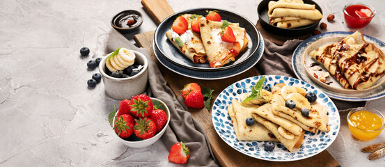 Sweet crepes assortment with berries chocolate on gray background.