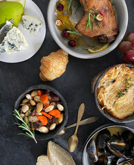 French dishes and appetizers served on dark background.