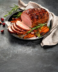 Baked ham with vegetables on dark background.