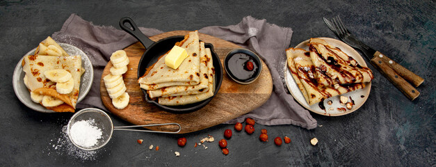 Crepes with sweet toppings on dark background.