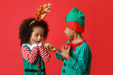Little African-American children with Christmas balls on red background