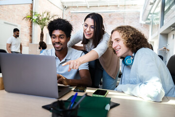 Smiling young multiracial coworkers working together on business strategy using laptop.