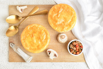 Wooden board tasty vegetable pot pies on white background
