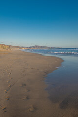 A calm sunset on the beach with ocean waves and mountains in the background Todos Santos Baja California Sur. Mexico