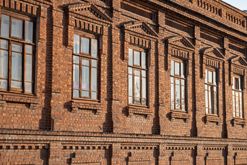 Brick wall of an old 19th century building with large windows. Wall of an old red brick building with six windows