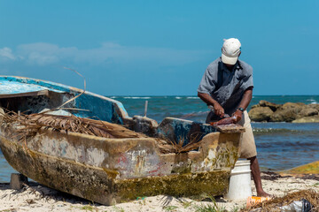 an elderly fisherman preparing a dorado fish for cooking, concept of work on the beach in dominican republic