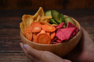 Close up woman holding wooden bowl with mixed vegetable chip dehydrated snack.