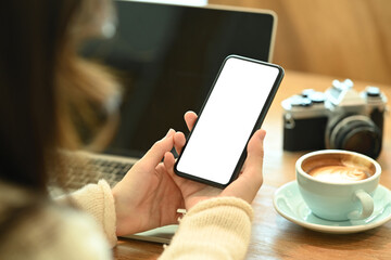 Over shoulder view of young woman holding smart phone with empty display.