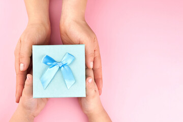 Hands of woman giving a paper gift box to a child.