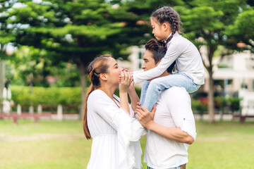 Portrait of enjoy happy love asian family father and mother holding hug  cute little asian girl child smiling playing and having fun moments good time in summer park at home