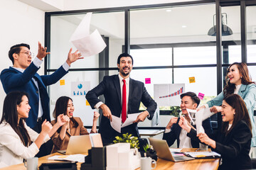 Successful group of casual business relaxing and throwing paper winning success agreement.Creative business people celebrating with arms up.Teamwork and success concep