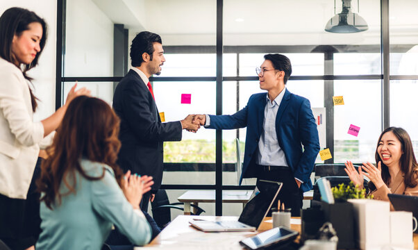 Image two asian business partners successful handshake together in front of group teamwork casual business clapping hands winning success agreement in modern office.Partnership approval and teamwork