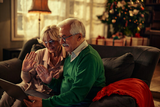 Senior couple waving and celebrating Christmas online