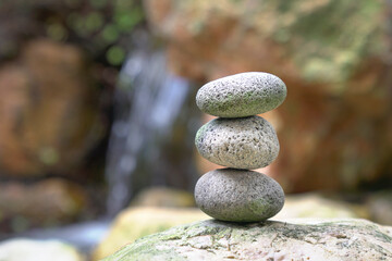 Stones stacked on top of each other with mini waterfall at the background. Balance, zen and harmony concept.