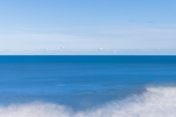 青い空と青い海が作る地平線と寄せる波が作る白い抽象、長秒露光