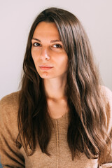 Millennial young pretty woman at home sitting on the couch. Confident and healthy portrait. Long brown hair and big eyes beautiful woman