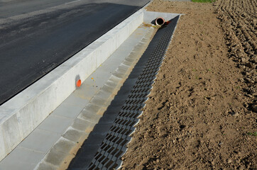 on the side of the road there is a concrete wall support and a ditch reinforced with perforated...