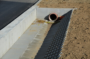 on the side of the road there is a concrete wall support and a ditch reinforced with perforated tiles. drains and drains away rainwater from the road and from the field.