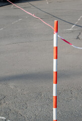 On the background of an asphalt square striped fence post with a signal tape