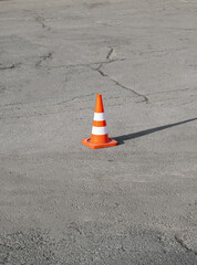 On asphalt road in cracks striped orange traffic cone