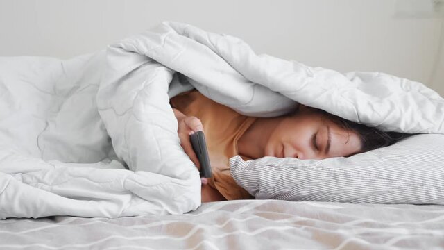 Young woman goes to sleep with teddy bear in her bedroom. Phone addiction, insomnia. Checking social media. Circadian rhuthm.