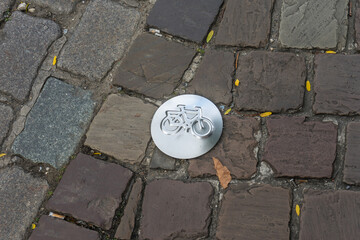 Antwerp, Belgium, silver metal cycle symbol on cobble stone paved street