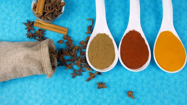 A sack full of star anise spice falling near Jeera  red chili  and turmeric powder . Exotic spices star anise and cinnamon - cooking ingredients  Indian kitchen