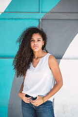 Portrait of a teenage Cuban girl in front of a colorful wall in shades of blue, closeup hispanic multiracial teenager woman
