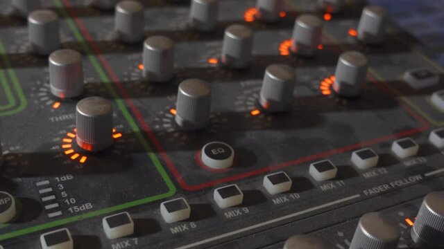 A Person Pressing the EQ Button on a Music Mixer Board