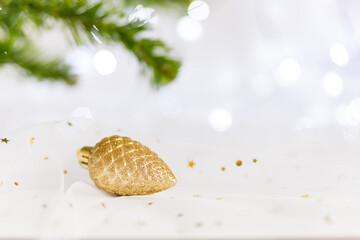branches of a Christmas tree and a Christmas tree toy- a cone on a white background. Blurry lights from the garland are visible in the background. Soft focus. copy space