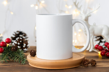 Fototapeta na wymiar Winter mockup white ceramic coffee cup and Christmas decoration on a wooden table background. Copy space for creative advertising text message or promo content