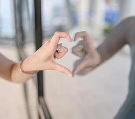 Woman's hand making a heart shape by hands in the mirror.