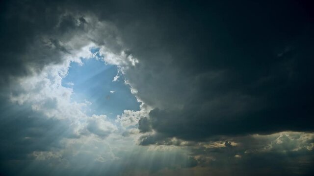 4K Sun Rays Shining Through Dark Storm Cloudy Rainy Sky With Fluffy Rain Clouds. Sky Natural Background. Weather Forecast Concept