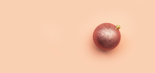 Shiny pink Christmas ball on pale pink background, copy space banner